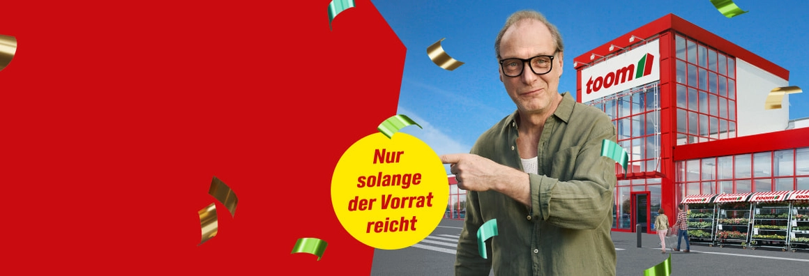 Ein Mensch mit Brille steht vor einem Baumarkt und deutet auf einen Hinweis.